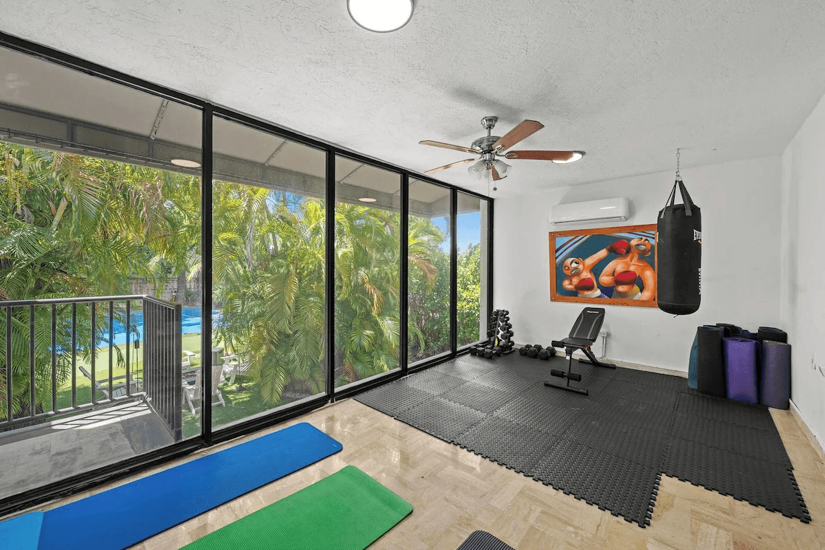 Private gym with weights, mats, and a punching bag